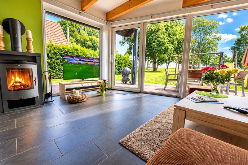 Living area in Benno with wood-burning stove, light green wall and view of terrace and garden