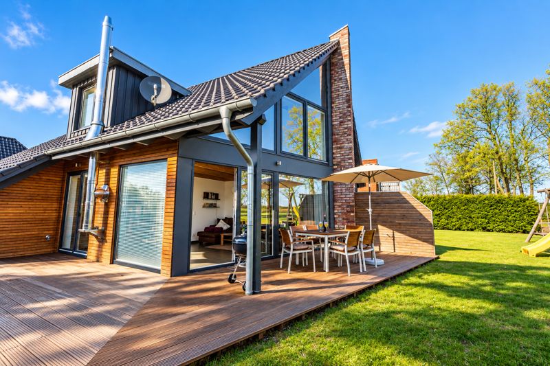 Garden side of Thea with large wooden terrace and glass front