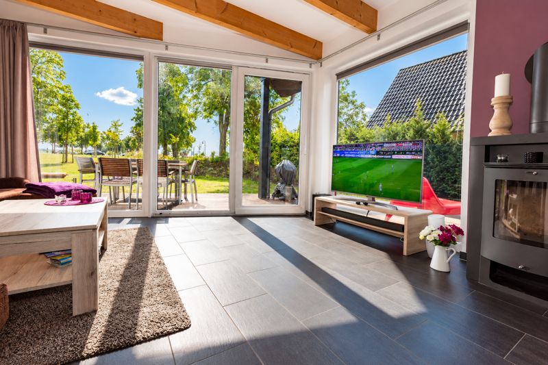 Living area in Thea with purple wall, wood-burning stove and large windows onto the terrace